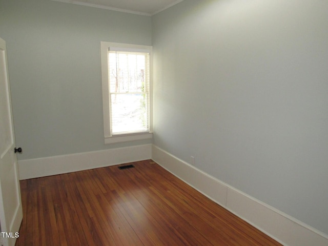 spare room featuring crown molding and dark hardwood / wood-style flooring