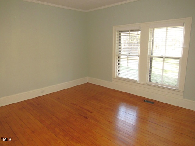 empty room with crown molding and wood-type flooring