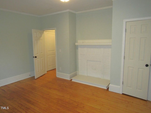 unfurnished bedroom featuring a fireplace, crown molding, and light hardwood / wood-style flooring