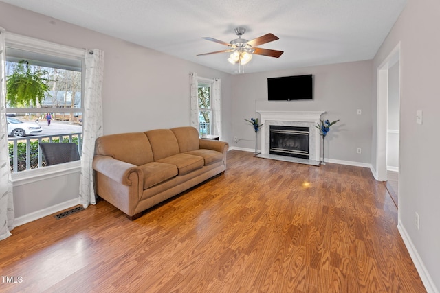 living room featuring a fireplace, ceiling fan, wood-type flooring, and a healthy amount of sunlight