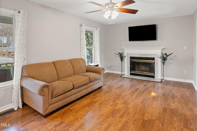 living room featuring hardwood / wood-style floors, ceiling fan, and a premium fireplace