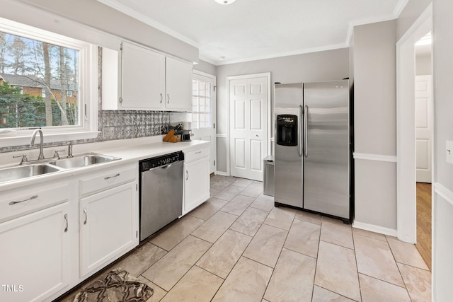 kitchen with appliances with stainless steel finishes, tasteful backsplash, ornamental molding, sink, and white cabinetry