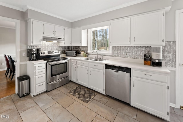 kitchen with appliances with stainless steel finishes, white cabinets, crown molding, backsplash, and sink