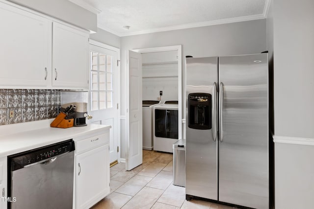 kitchen featuring washing machine and dryer, light tile patterned flooring, crown molding, stainless steel appliances, and white cabinets