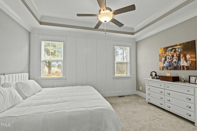 carpeted bedroom featuring ceiling fan, ornamental molding, and a tray ceiling