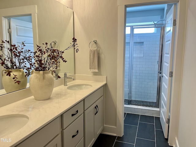 full bathroom featuring a shower stall, a sink, double vanity, baseboards, and tile patterned floors