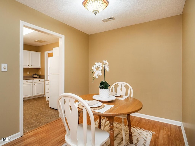 dining space featuring a textured ceiling and light wood-type flooring