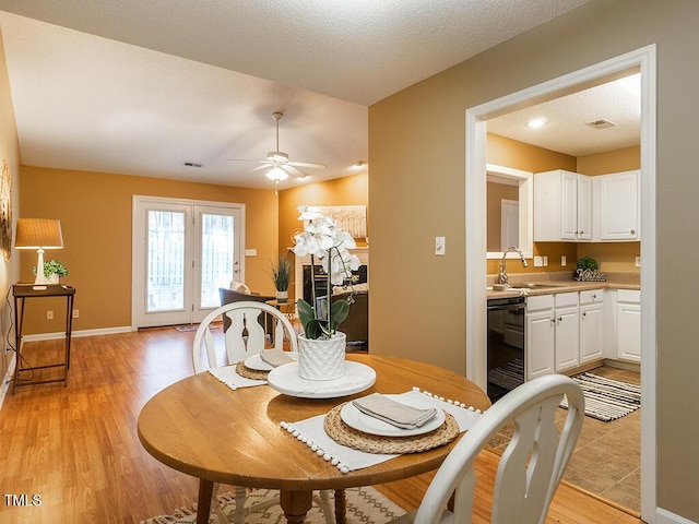 dining space with sink, light hardwood / wood-style floors, a textured ceiling, and ceiling fan