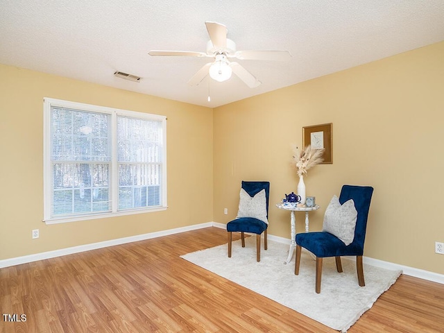 sitting room featuring wood-type flooring, ceiling fan, and a textured ceiling