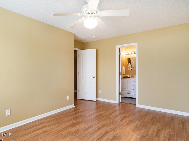 unfurnished bedroom with ceiling fan, connected bathroom, light hardwood / wood-style floors, and a textured ceiling