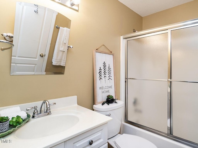 full bathroom featuring vanity, combined bath / shower with glass door, and toilet