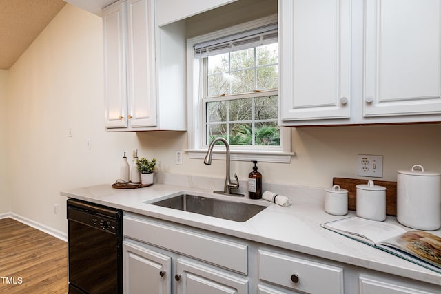 kitchen with sink, light stone countertops, white cabinets, and black dishwasher