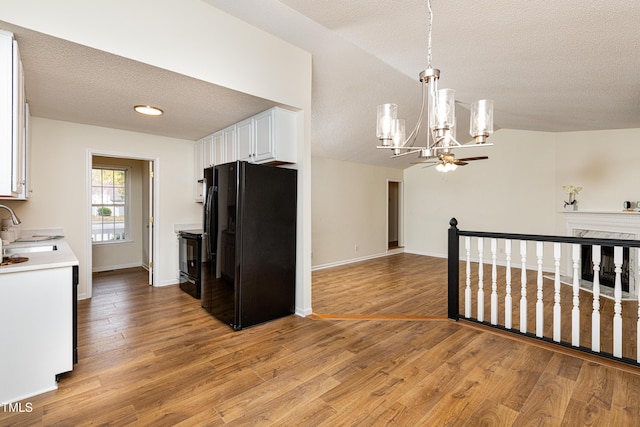 kitchen featuring sink, black appliances, pendant lighting, light hardwood / wood-style floors, and white cabinets