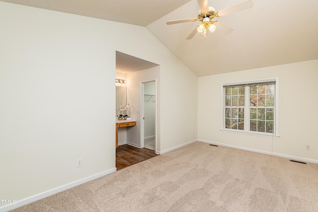 interior space with ceiling fan, vaulted ceiling, and a textured ceiling