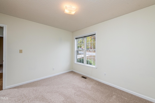 carpeted empty room featuring a textured ceiling