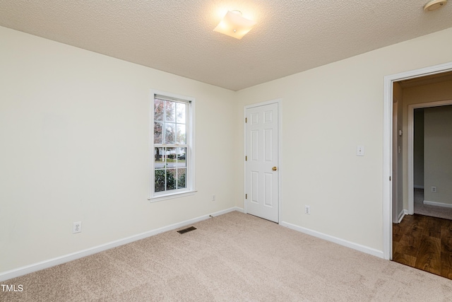 unfurnished room with carpet flooring and a textured ceiling