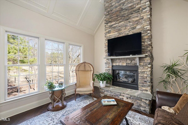 living room with beamed ceiling, high vaulted ceiling, a stone fireplace, and hardwood / wood-style floors