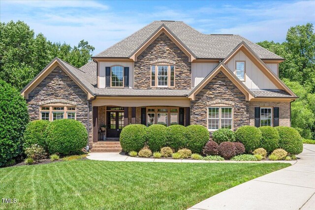 2933 Elmfield St, Raleigh, NC 27614 - craftsman-style home with stone siding, a front yard, french doors, covered porch, and a shingled roof