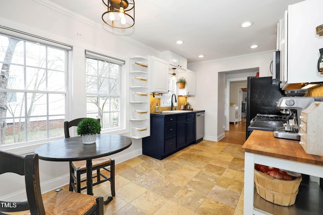 kitchen featuring butcher block countertops, sink, ornamental molding, stainless steel appliances, and white cabinets