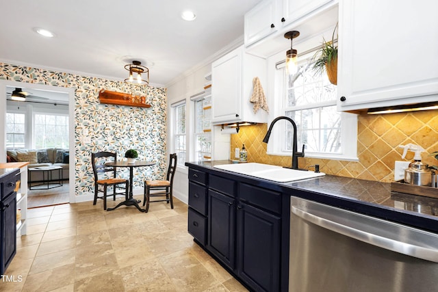 kitchen featuring stainless steel dishwasher, sink, hanging light fixtures, and white cabinets