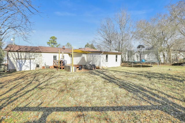 back of house featuring a deck, a yard, and a trampoline