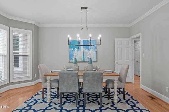 dining room featuring an inviting chandelier, crown molding, and light wood-type flooring