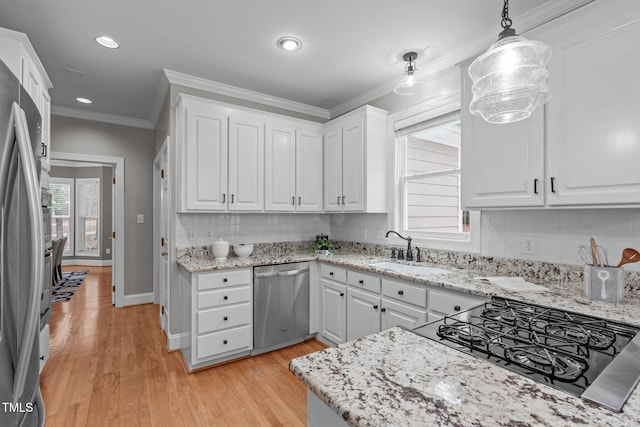 kitchen featuring appliances with stainless steel finishes, decorative light fixtures, sink, white cabinets, and ornamental molding