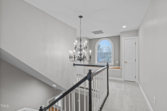 hallway featuring light carpet and a chandelier