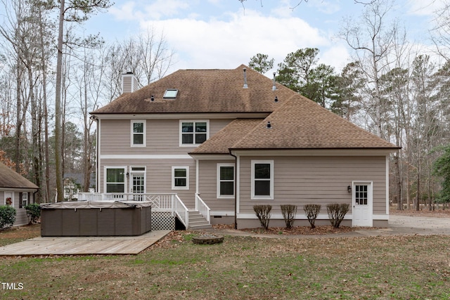 rear view of house with a yard, a hot tub, and a deck