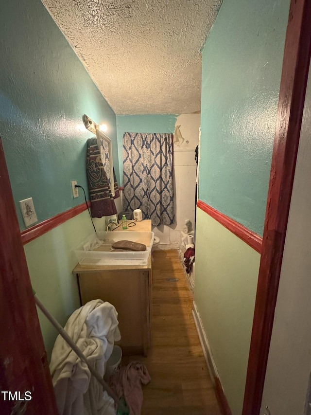 bathroom featuring wood-type flooring, vanity, and a textured ceiling