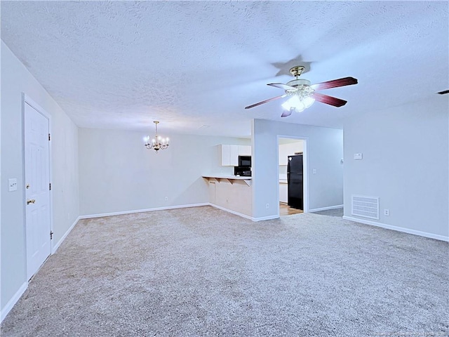 unfurnished living room featuring ceiling fan with notable chandelier, light colored carpet, and a textured ceiling