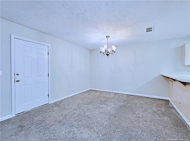 carpeted spare room with an inviting chandelier and a textured ceiling