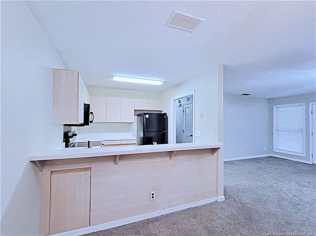 kitchen featuring a breakfast bar, carpet, black appliances, a textured ceiling, and kitchen peninsula