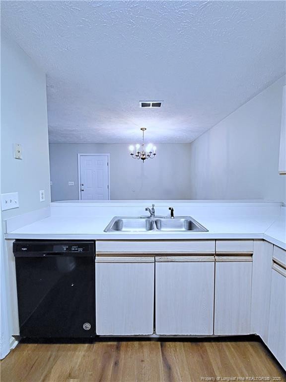 kitchen with pendant lighting, sink, light hardwood / wood-style flooring, black dishwasher, and a textured ceiling