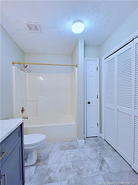 full bathroom featuring vanity, a textured ceiling, toilet, and washtub / shower combination