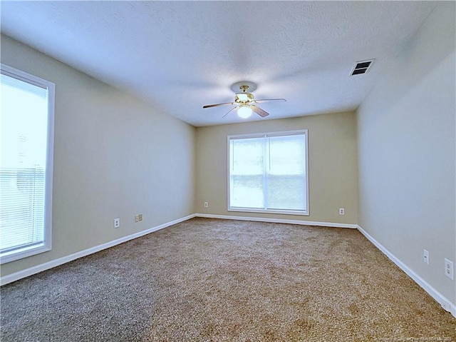 carpeted empty room with ceiling fan, a healthy amount of sunlight, and a textured ceiling