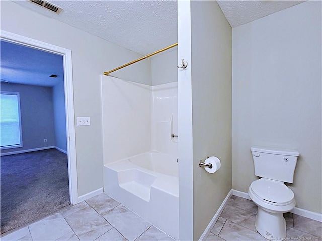 bathroom with shower / tub combination, toilet, tile patterned flooring, and a textured ceiling