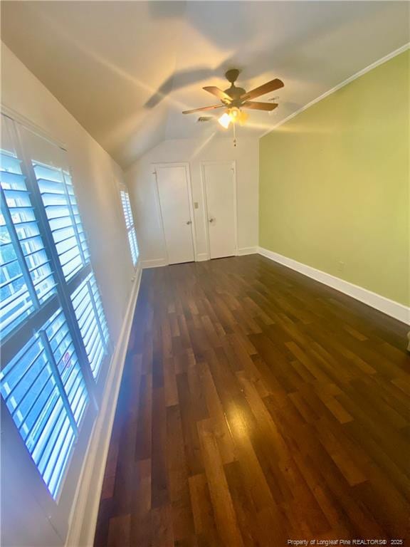 empty room with ceiling fan, lofted ceiling, and dark hardwood / wood-style flooring