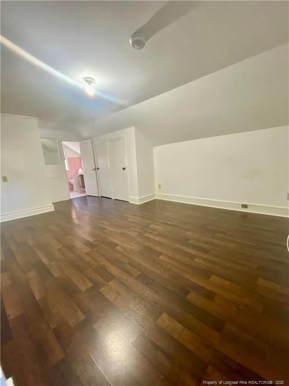 additional living space featuring lofted ceiling and dark hardwood / wood-style flooring