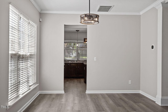 unfurnished dining area featuring sink, wood-type flooring, and ornamental molding