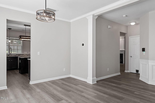 unfurnished dining area with ornate columns, crown molding, sink, and hardwood / wood-style floors