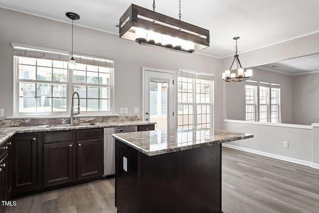 kitchen featuring sink, hanging light fixtures, a center island, ornamental molding, and light stone countertops