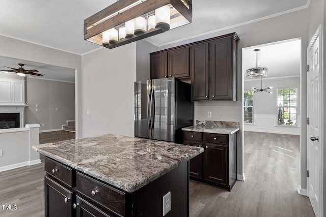 kitchen with a kitchen island, wood-type flooring, ornamental molding, fridge, and ceiling fan