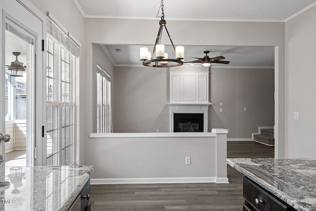 kitchen with ceiling fan with notable chandelier, decorative light fixtures, dark hardwood / wood-style flooring, ornamental molding, and light stone countertops