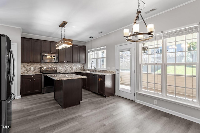 kitchen with pendant lighting, dark brown cabinets, a kitchen island, and appliances with stainless steel finishes