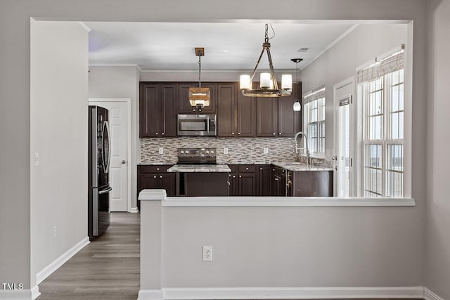 kitchen with pendant lighting, sink, dark brown cabinets, and stainless steel appliances