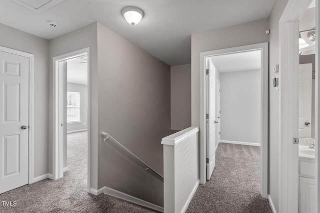 hall with dark colored carpet and sink