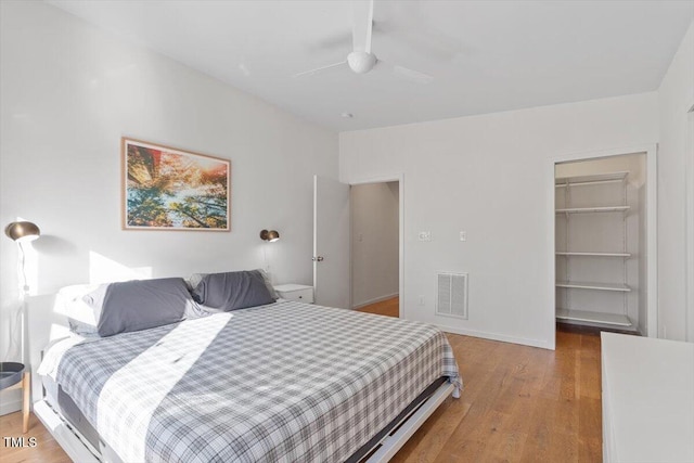 bedroom with wood-type flooring, a spacious closet, ceiling fan, and a closet