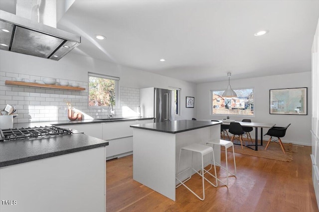 kitchen with range hood, sink, white cabinets, a center island, and stainless steel appliances