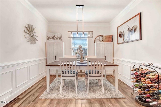 dining room with ornamental molding and light hardwood / wood-style flooring